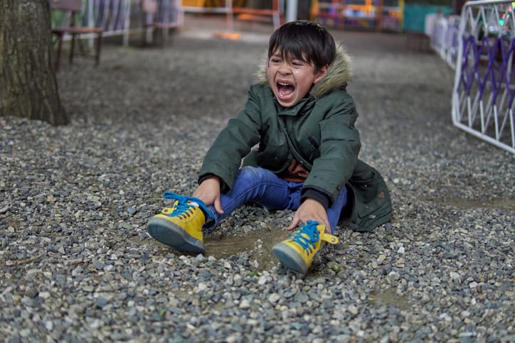 Upset child crying while sitting in a amusement park.