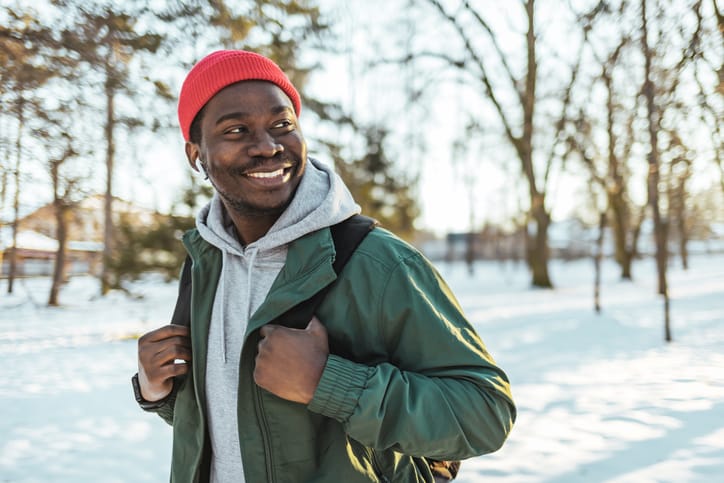 Young man walking in winter forest.
