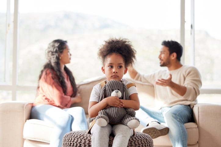 An upset little girl with her arguing parents.