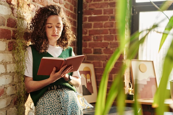 woman leaning against wall reading