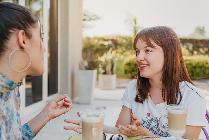 two women chatting outside with drinks