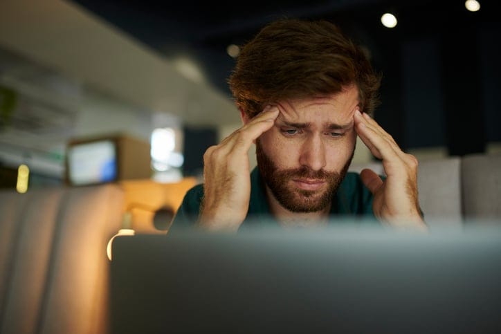 Entrepreneur working on laptop with headache.