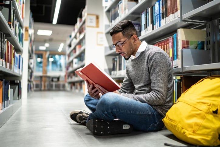 Man sitting on the ground at the library.