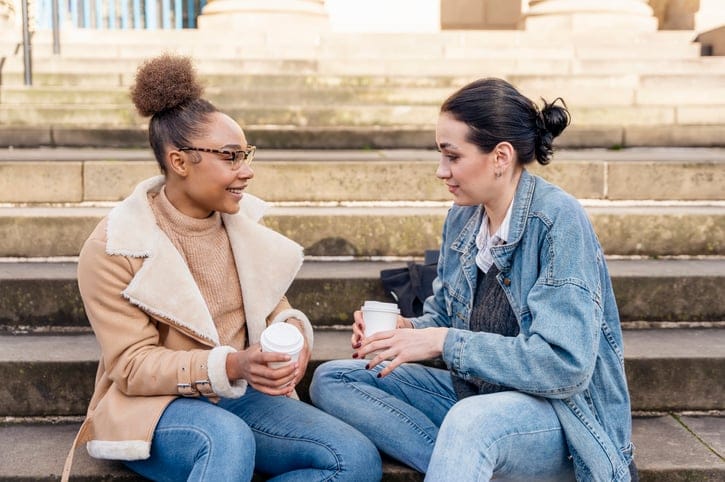 two female friends chatting on cement steps