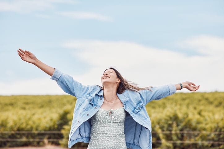 Happy, freedom and smile with woman in nature for peace, relax and youth with blue sky mockup. Journey, adventure and happiness with girl enjoying outdoors for summer break, vacation and holiday