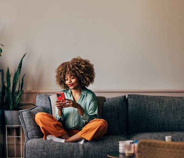 A woman texting on her couch at home.