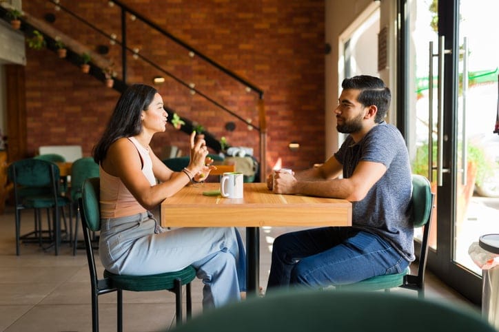 Beautiful latin couple talking and smiling looking happy while having a coffee date at a beautiful cafe