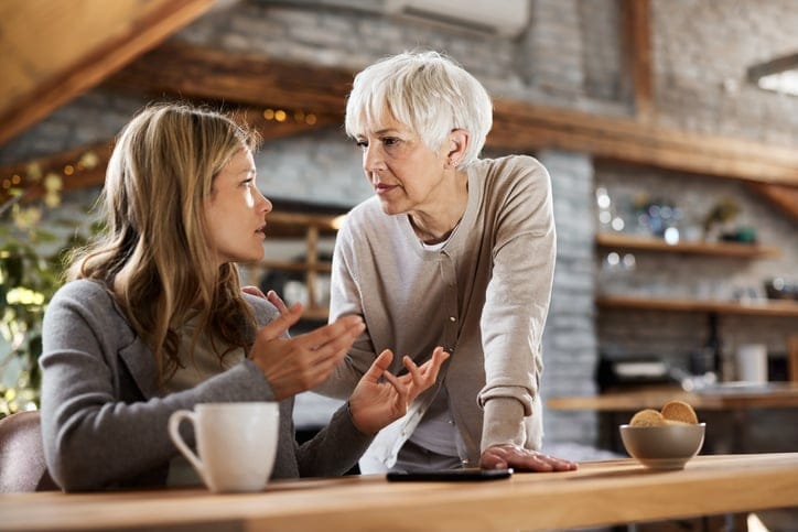 Single mature mother talking to her depressed adult daughter at home.