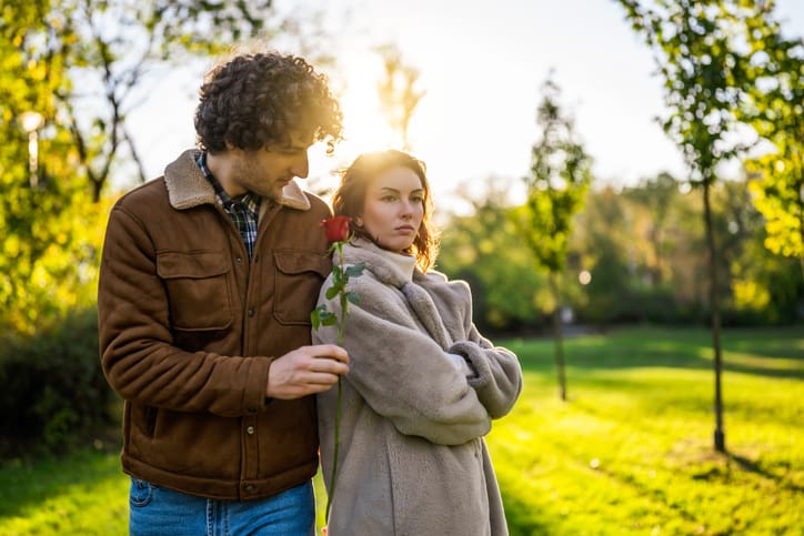 Man trying to apologize to a woman with a rose. 
