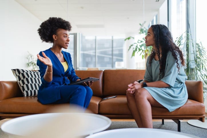 Two women chatting on a sofa.