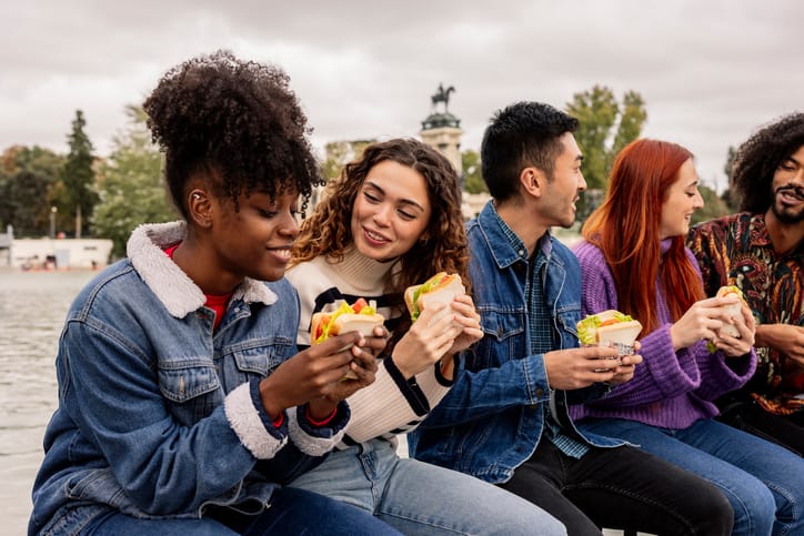Friends eating lunch while laughing outside. 