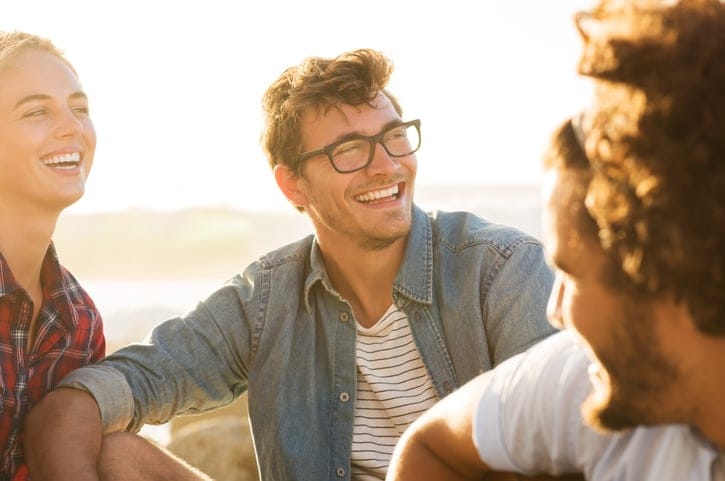 Smiling guy on beach with friends.