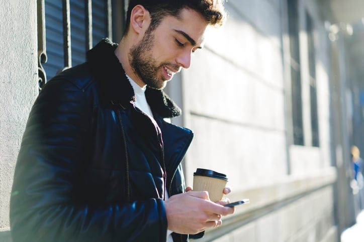 Young man on phone standing outdoors.