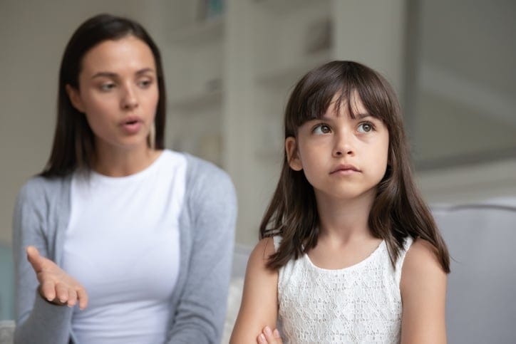 Mother engaging her young daughter in conversation, while the daughter seems disinterested.