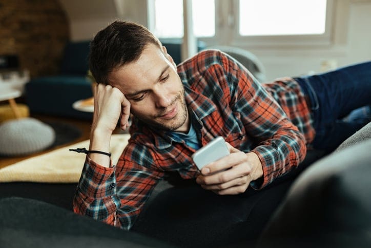 Smiling man reading text messages.