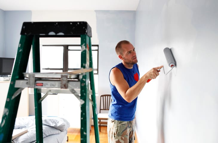 Man painting wall with roller.