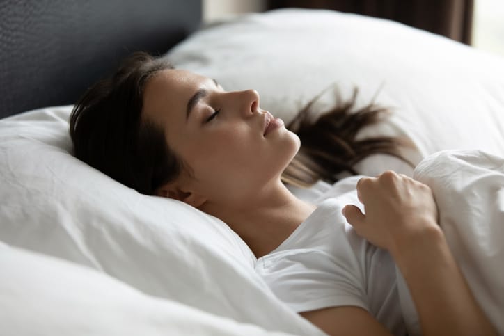 Woman lying comfy in bed asleep.