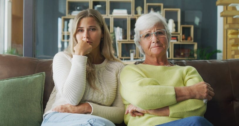 Young daughter and her mother looking worried at home.