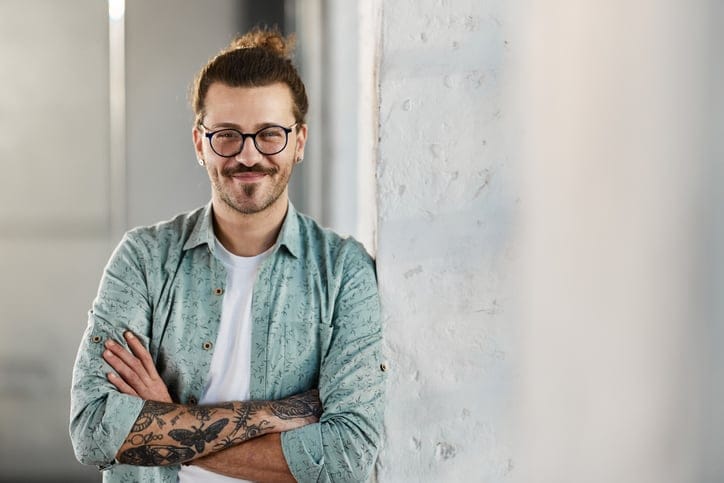 Confident man standing by a wall.