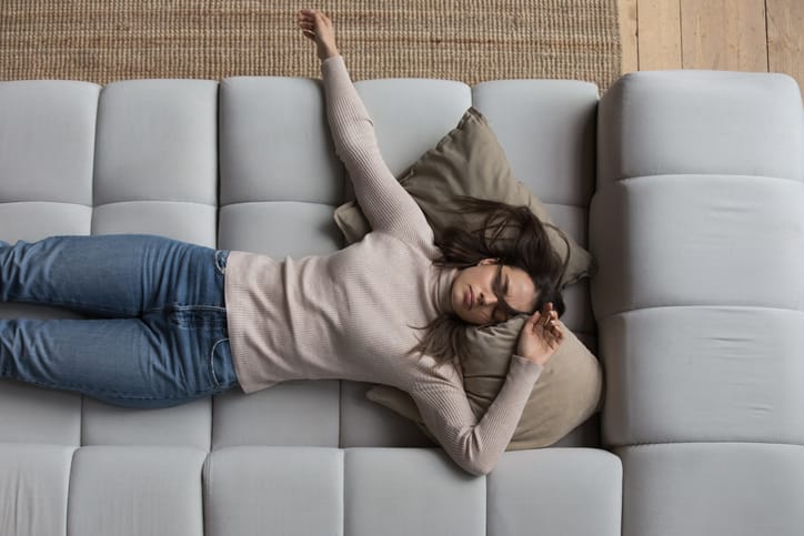 Sleepy girl in casual clothes resting on couch at home.