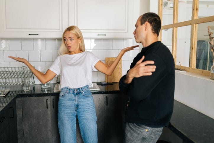 Husband ignoring angry wife and arguing in kitchen.