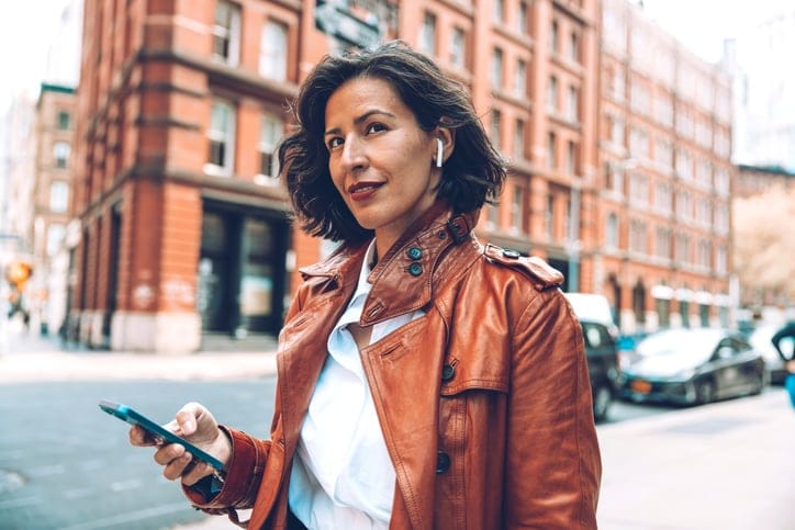 Fashionable woman walking to the office on earphones.