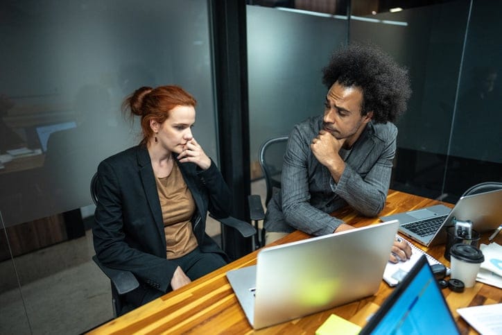 Worried coworkers talking on a board room at the office.