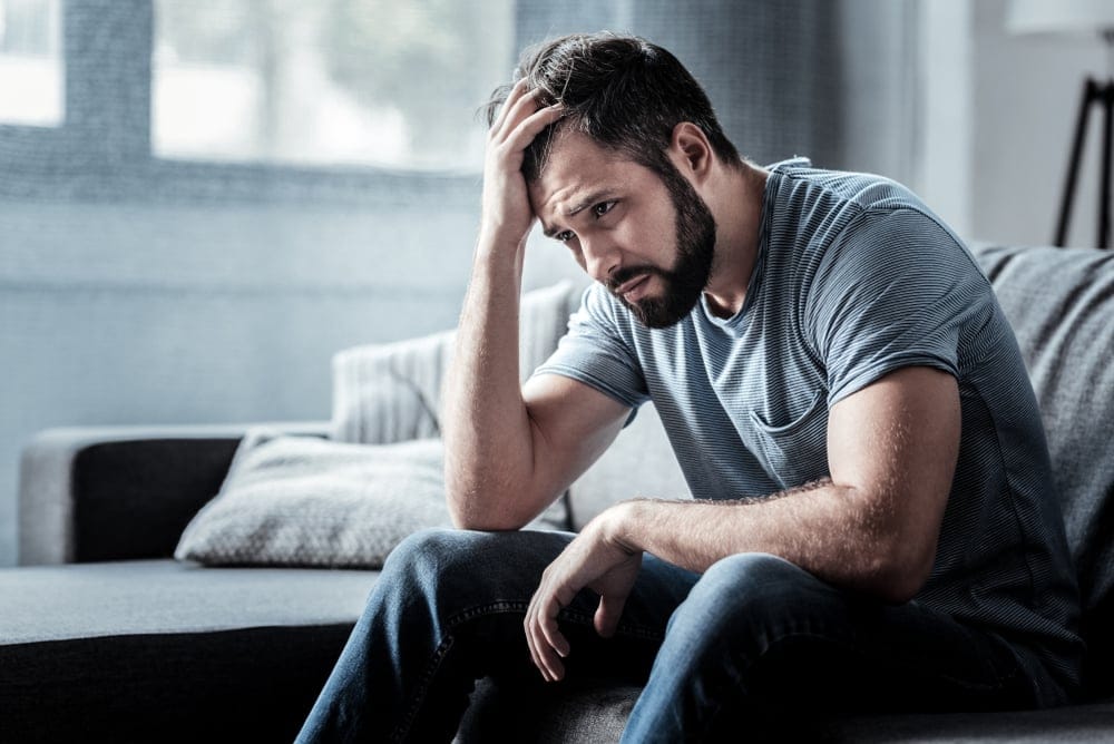 Man sitting down expressing pain.