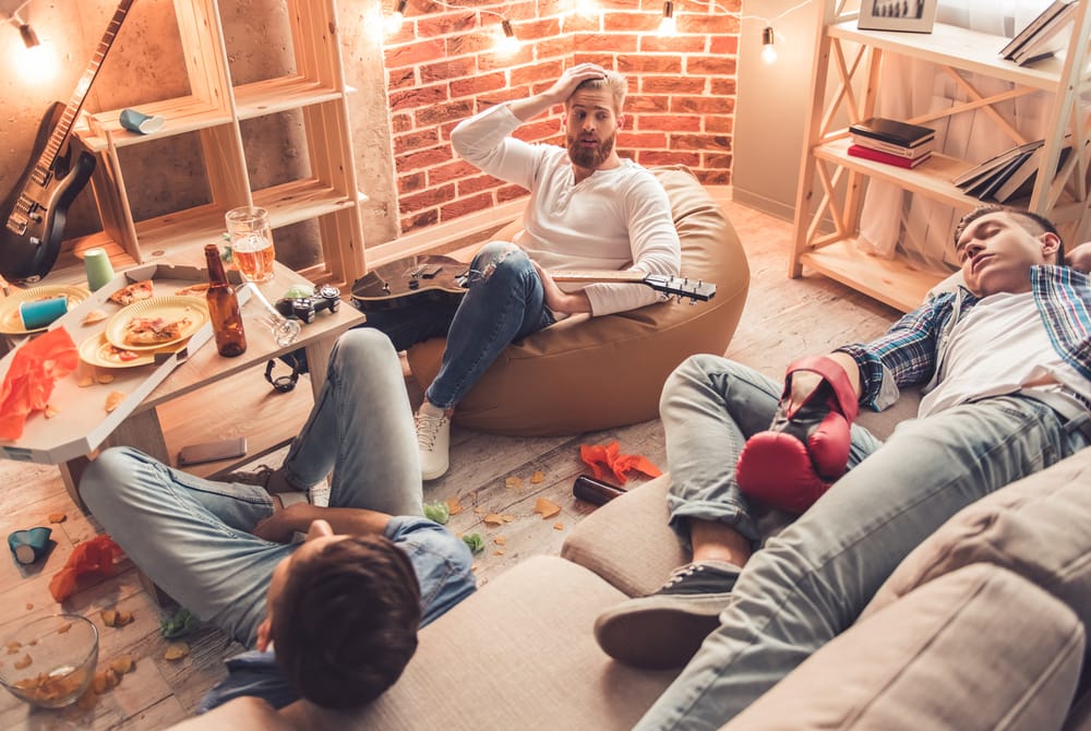 Men sleeping in a messy room.