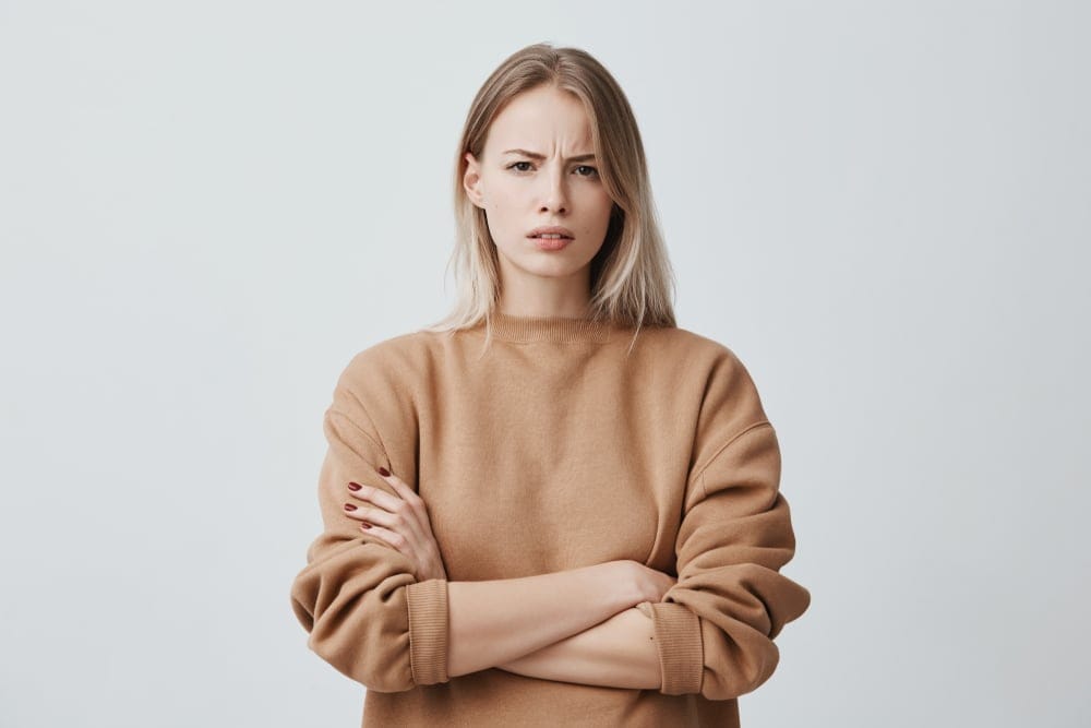 A woman frowning with crossed arms.
