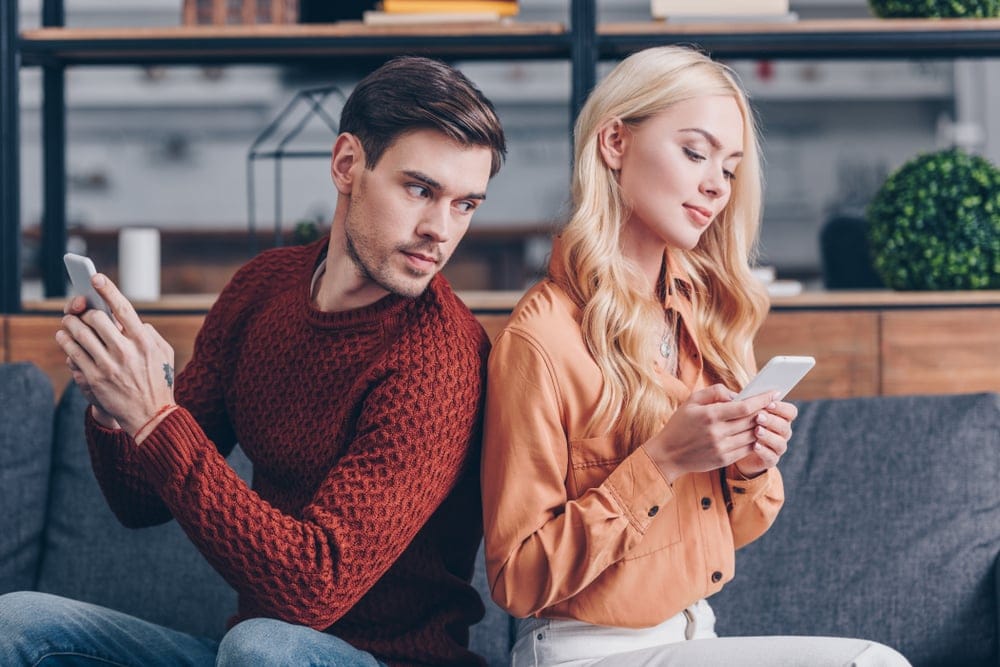 Couple sitting back to back looking unhappy.