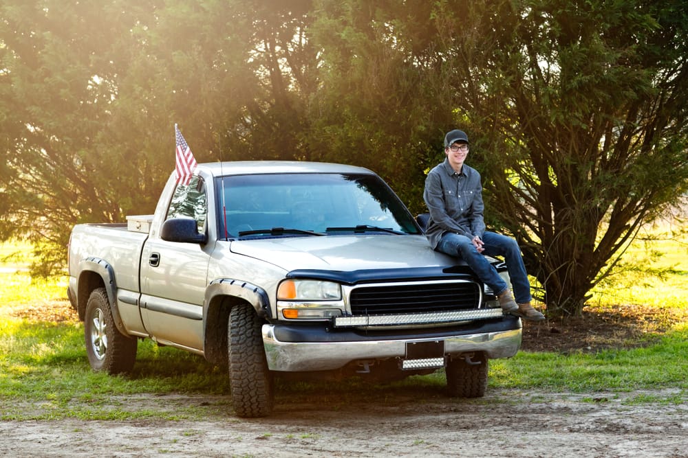 Teenage boy in hood of his truck.