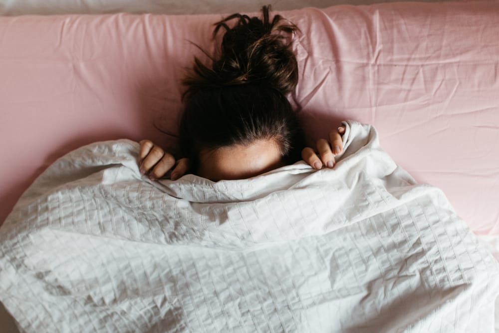 Woman hiding underneath blanket.