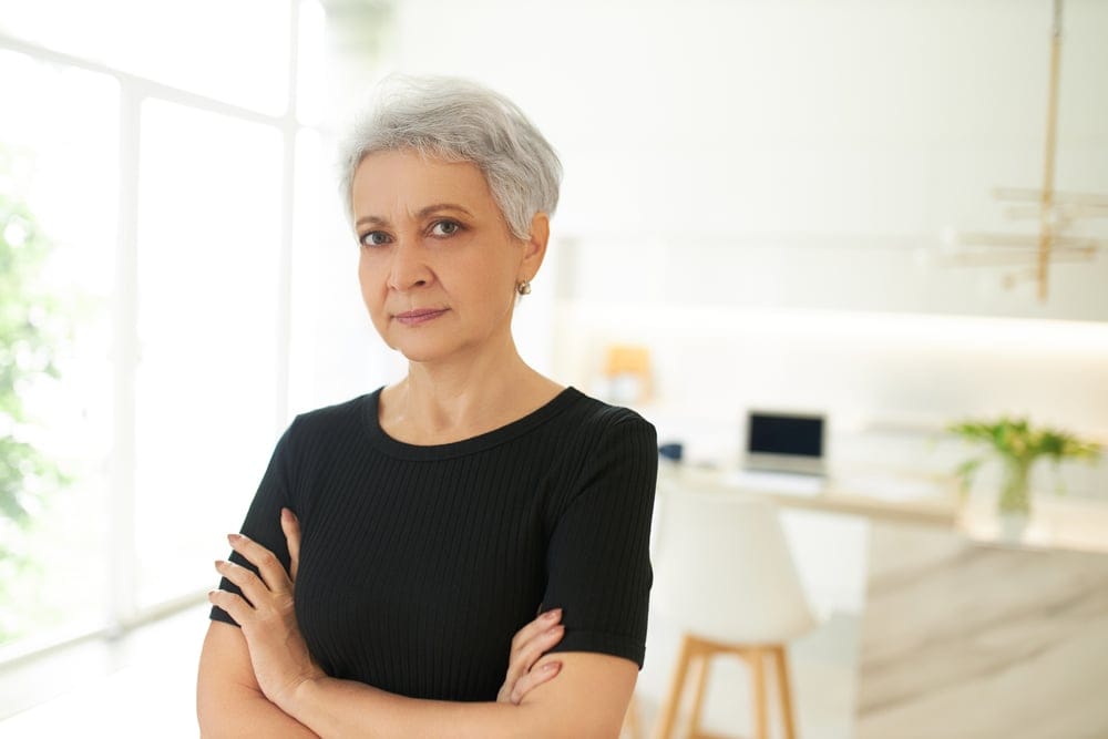 A serious middle aged woman in black shirt with cropped short gray hair