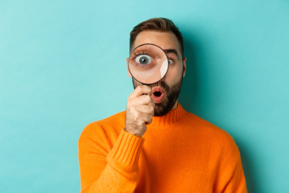 Man looking through a magnifying glass.