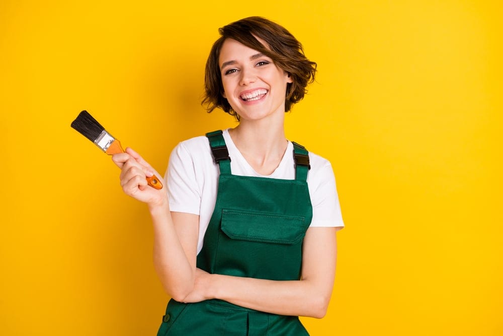 Woman smiling holding a paint brush.