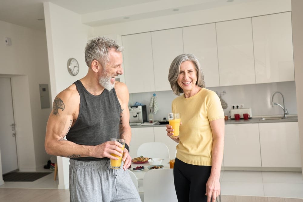 Man and woman laughing in their kitchen.