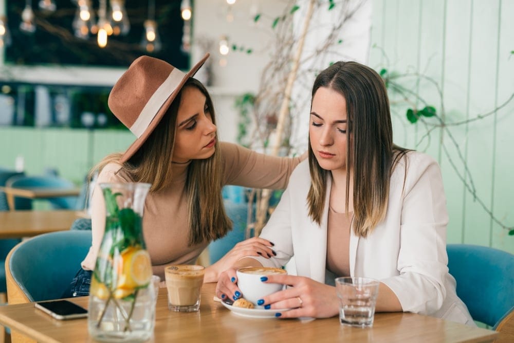 A young woman comforting her friend at a bar