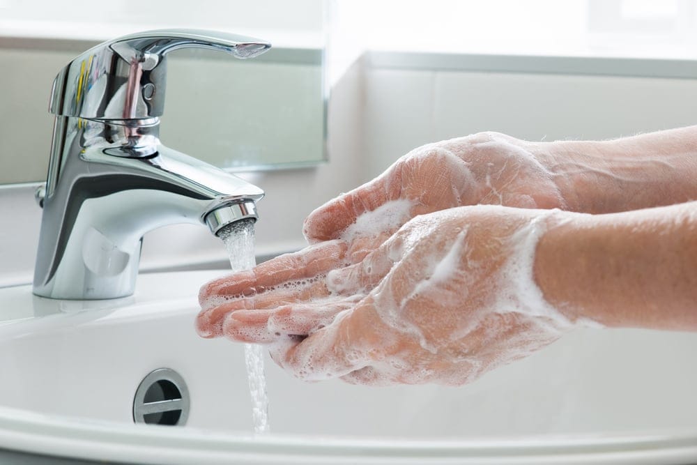Woman washing hands at sink.
