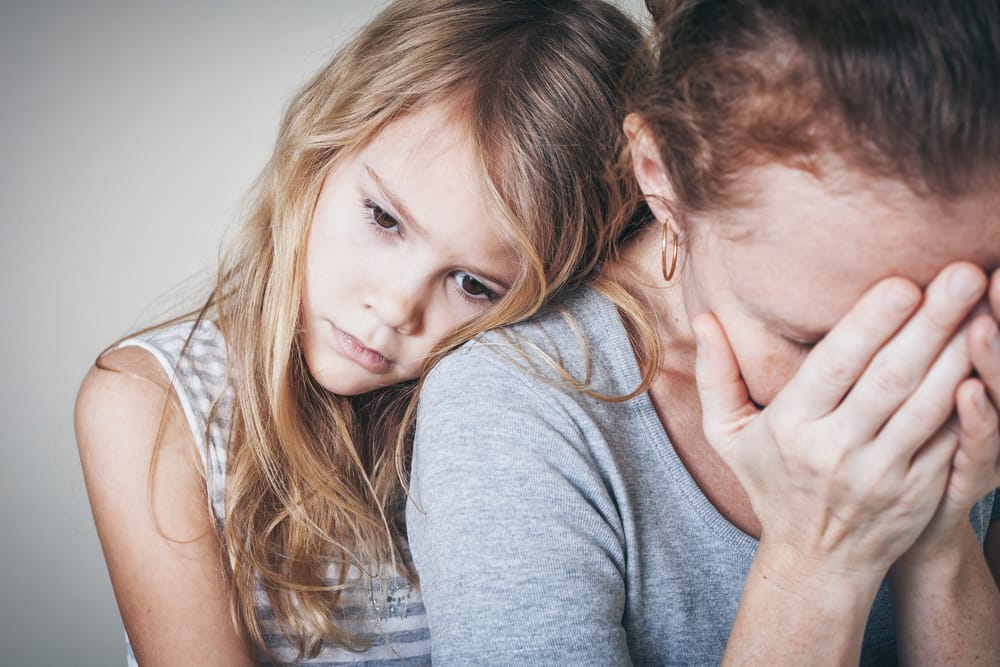 Sad girl hugging her upset mother.