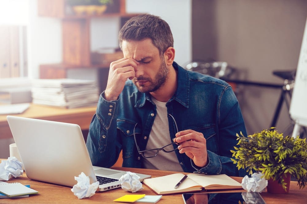Man feeling overwhelmed at his desk.