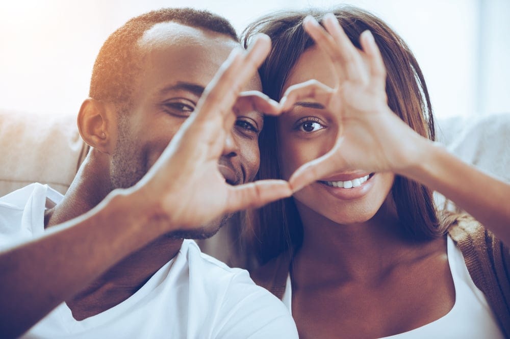 Couple putting up the hand heart sign together.