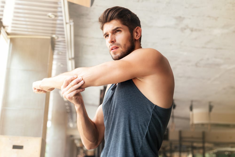A man warming up with stretches in the gym.