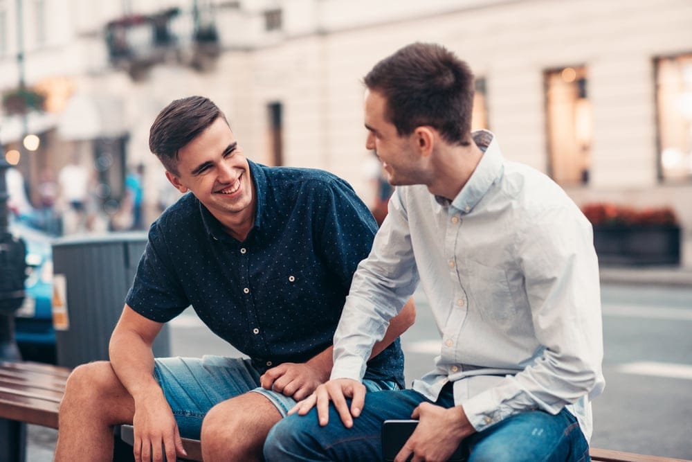 Two male friends talking outside.
