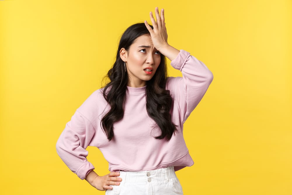 Woman with her hand on her head overwhelmed.