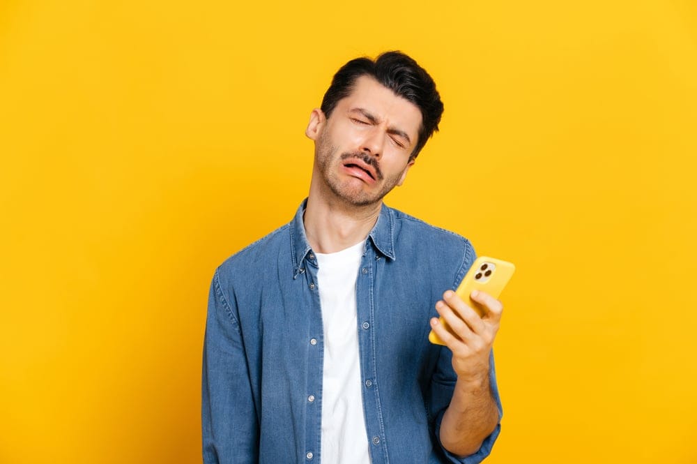 Man looking frustrated at his phone.