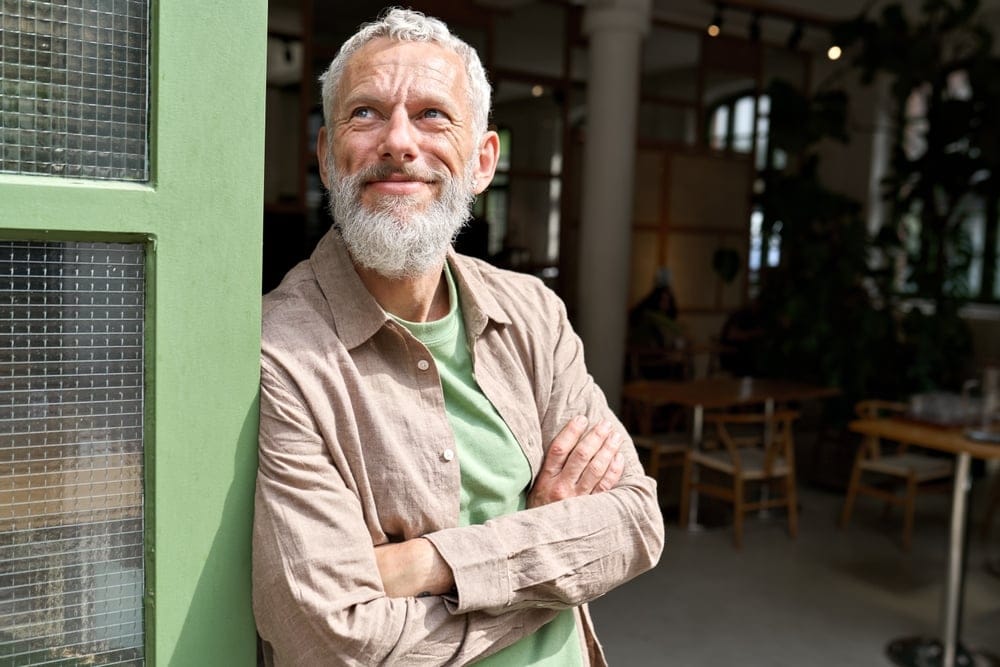 Older man smiling standing outside.