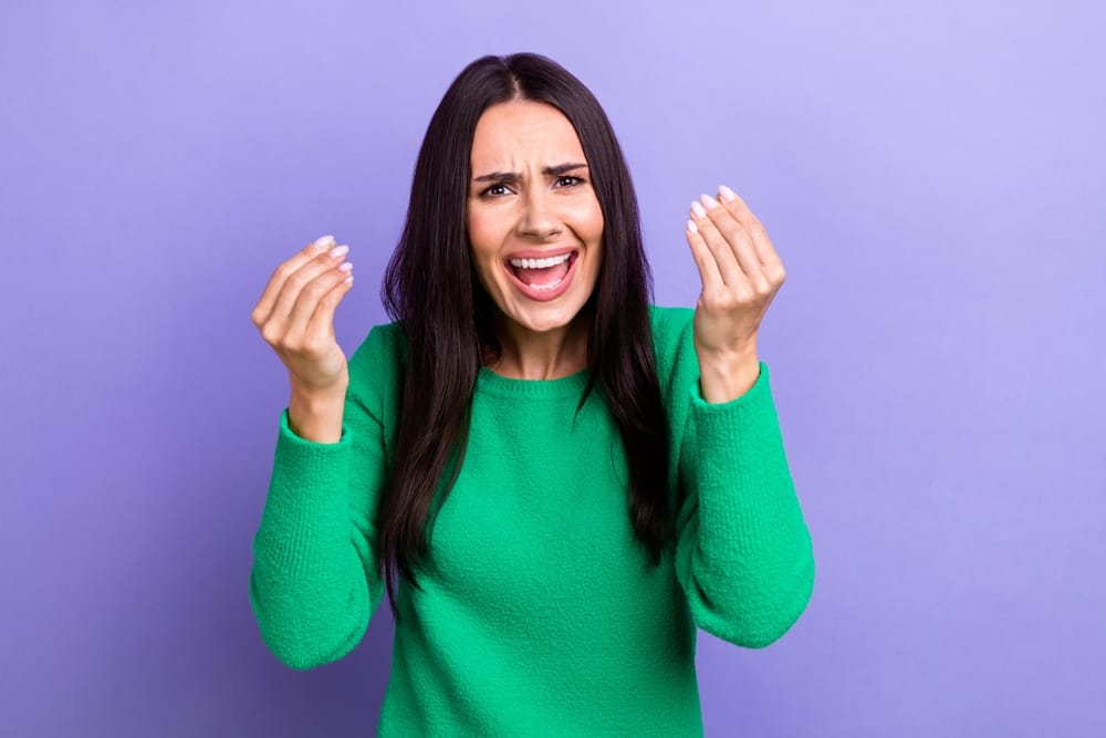 Woman holding her hands up looking angry.