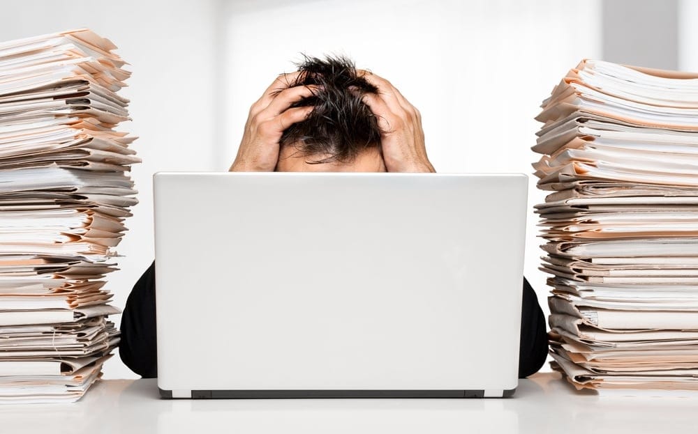 Man with work piled up at his desk.