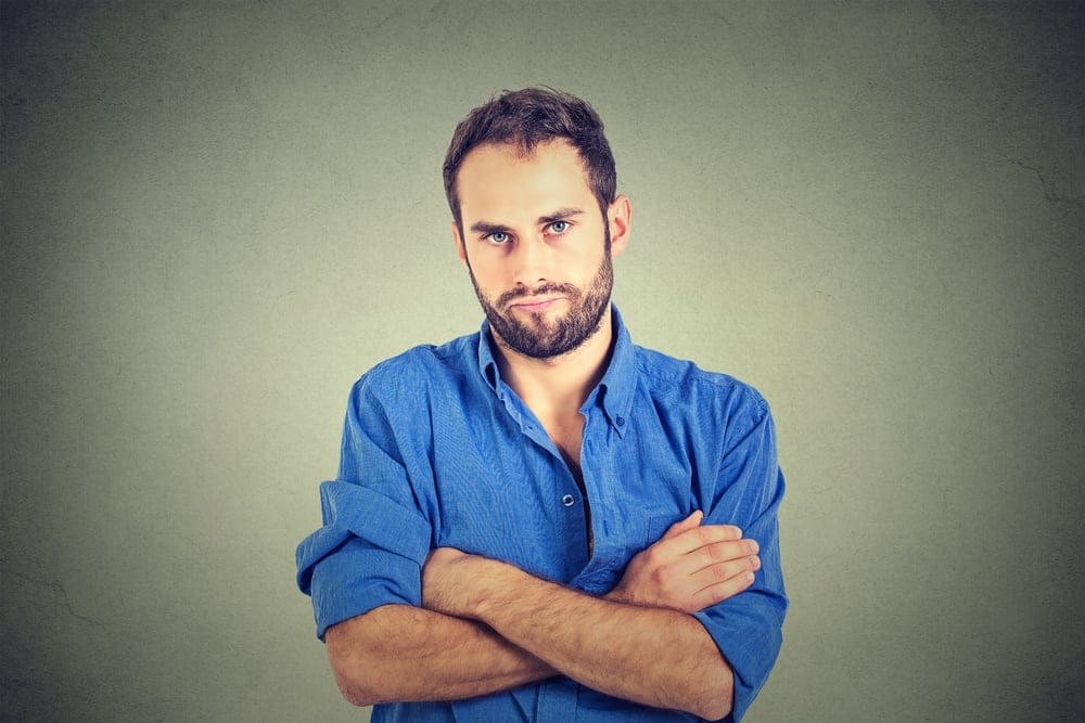 Man crossing his arms and looking mad.
